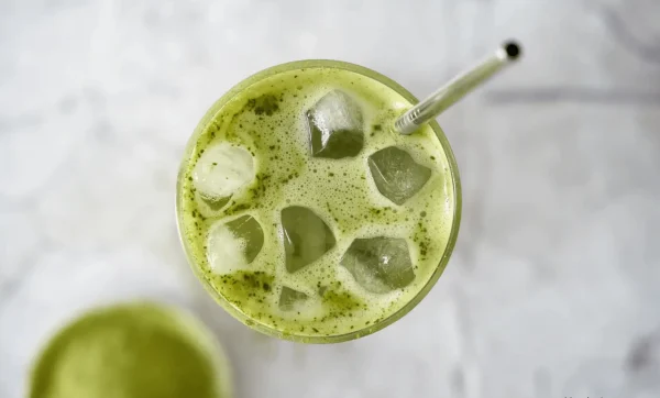 Iced matcha latte with ice cubes and a reusable straw
