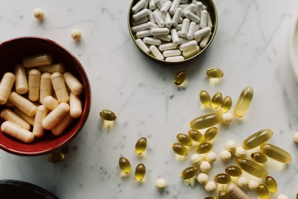 Assorted capsules, tablets, and softgels arranged on a marble surface for an article about supplements for hormonal acne.