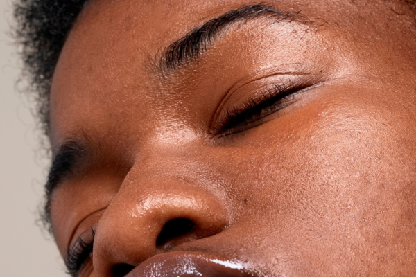 Close-up of a Black woman’s face with her eyes closed, showing natural skin texture.