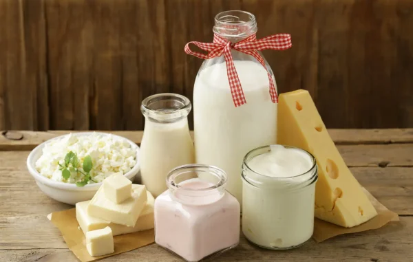 Milk, plain Greek yogurt and cheese arranged on a kitchen table for an article about dairy and acne-prone skin.