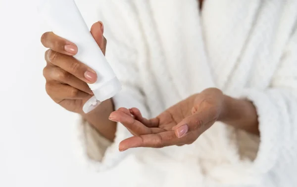 Woman applying moisturizer to the back of her hand while choosing skincare for oily skin.